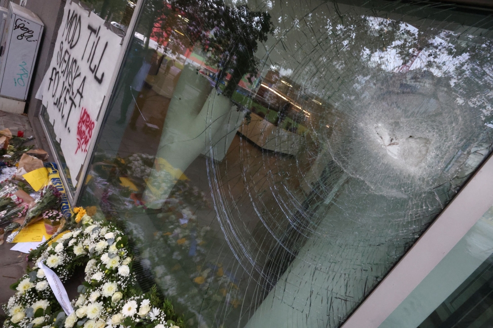 Flower wreaths placed by Swedish Prime Minister Ulf Kristersson and Belgian Prime Minister Alexander De Croo are seen underneath a damaged window, among flowers and other items left as a tribute to the victims two days after a gunman shot dead two Swedes, at the place of the shooting in Brussels, Belgium October 18, 2023. — Reuters pic