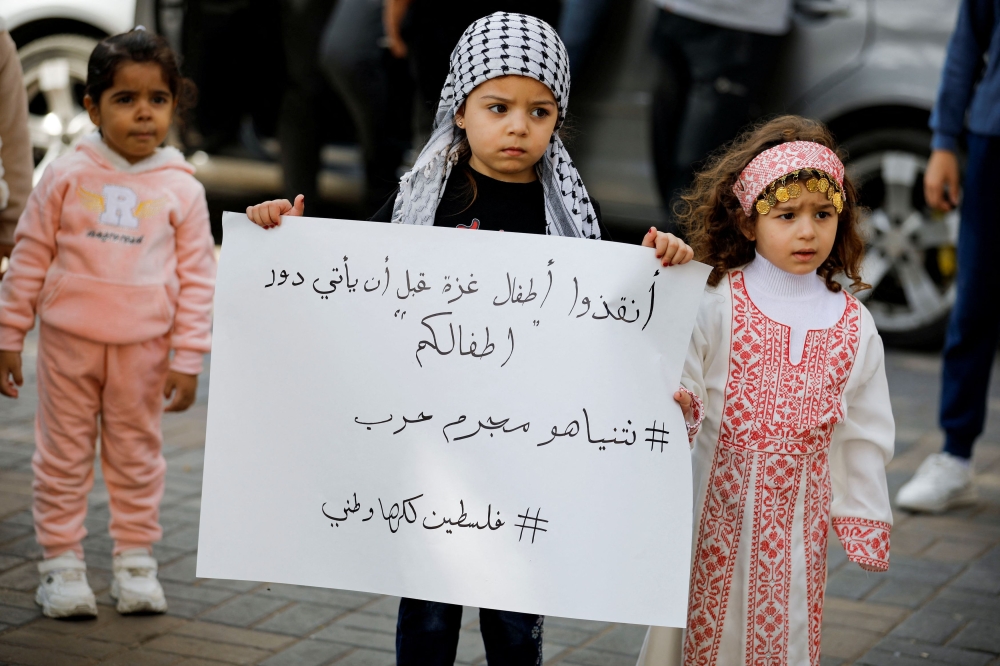 A child holds a placard as Palestinians take part in a protest in support of the people in Gaza, after hundreds of Palestinians were killed in a blast at Al-Ahli hospital in Gaza that Israeli and Palestinian officials blamed on each other, in Nablus in the Israeli-occupied West Bank October 18, 2023. — Reuters pic