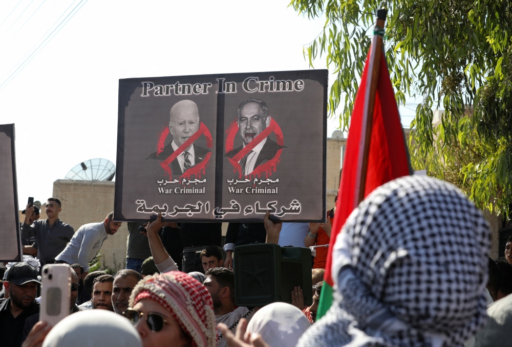 People hold a placard depicting US President Joe Biden and Israeli Prime Minister Benjamin Netanyahu during a pro-Palestinian protest, after hundreds of Palestinians were killed in a blast at Al-Ahli hospital in Gaza that Israeli and Palestinian officials blamed on each other, in Amman, Jordan, October 18, 2023. — Reuters pic 