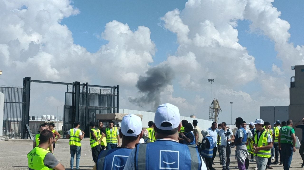 Egyptian volunteers look at the smoke rising from the Palestinian side at the Rafah crossing, as aid groups wait for the reopening of the crossing. — Reuters pic