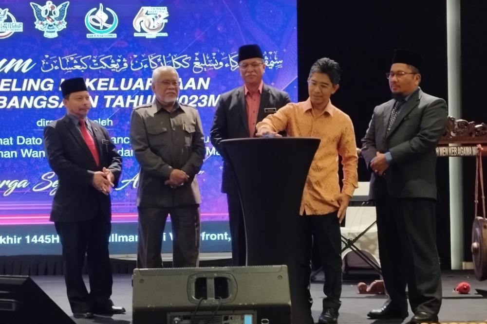 National Population and Family Development Board director-general Datuk Ahmad Shukor Abdullah presses the button to officiate the opening ceremony, as others look on. ― Borneo Post pic