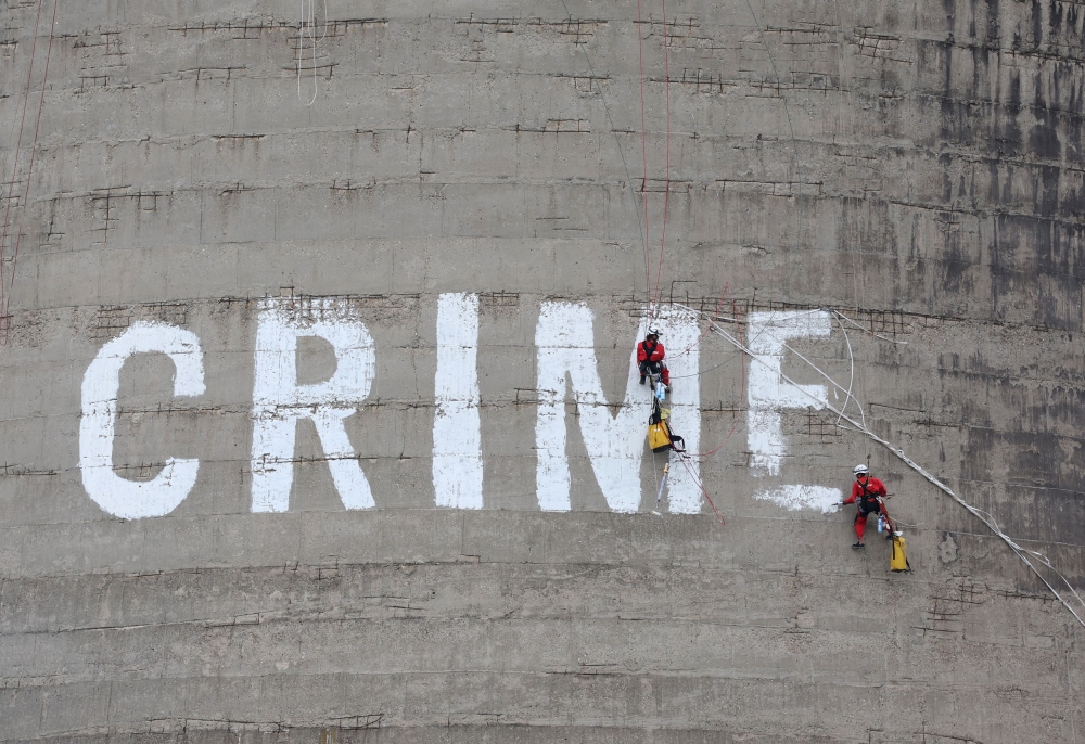 Activists from Greenpeace paint the word 'CRIME' on the 50-metres cooling tower of 'Maritza 3' thermal power plant during a protest in Dimitrovgrad, Bulgaria, October 16, 2023. — Reuters pic