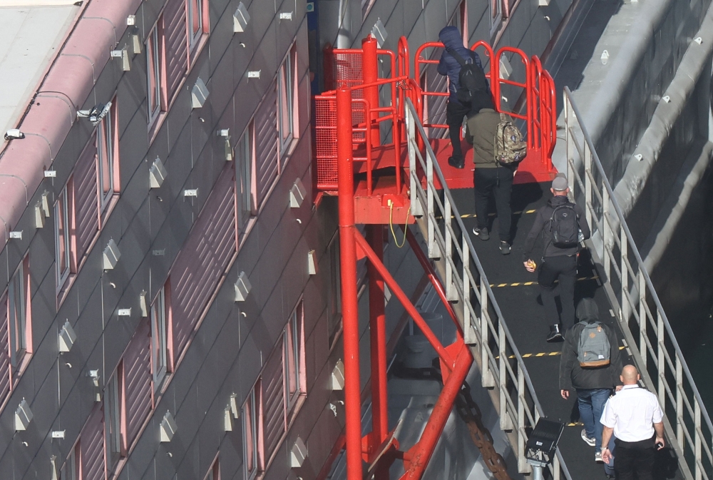 People, believed to be asylum seekers, arrive to be housed on the Bibby Stockholm accommodation barge at Portland Port, Portland near Weymouth in Britain, October 19, 2023. — Reuters pic