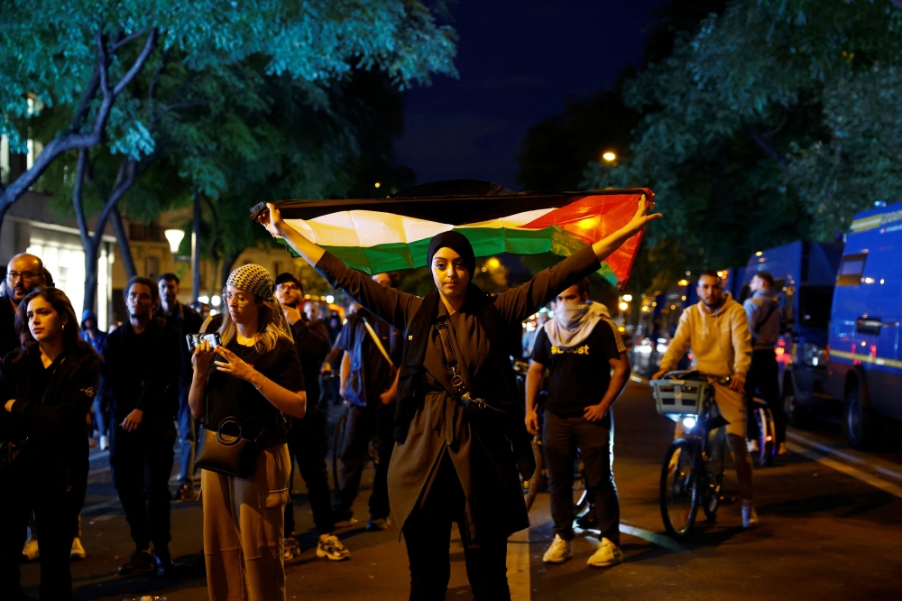 A woman holds a Palestinian flag during an unauthorized demonstration in support of Palestinians, as part of the ongoing conflict between Israel and the Palestinian Islamist group Hamas, at the Place de la Republique in Paris as French Interior Minister Gerald Darmanin ordered the systematic banning of pro-Palestinian demonstrations and the arrest of participants within France, October 12, 2023. — Reuters pic