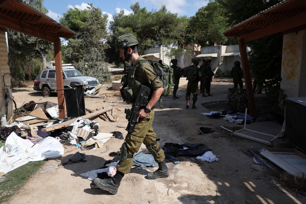 Members of the Israeli Defence Forces inspect buildings, following a deadly infiltration by Hamas gunmen from the Gaza Strip, in Kibbutz Kfar Aza, southern Israel, October 18, 2023. — Reuters pic