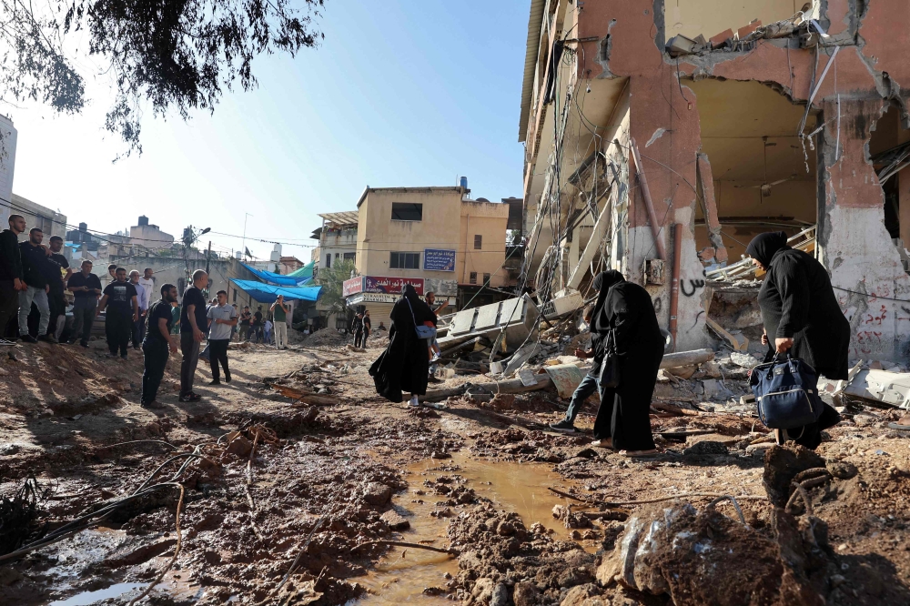 Palestinians walk next to a building damaged during a raid by Israeli troops at the Nur Shams refugee camp near the northern city of Tulkarm in the occupied West Bank on October 20, 2023. — AFP pic