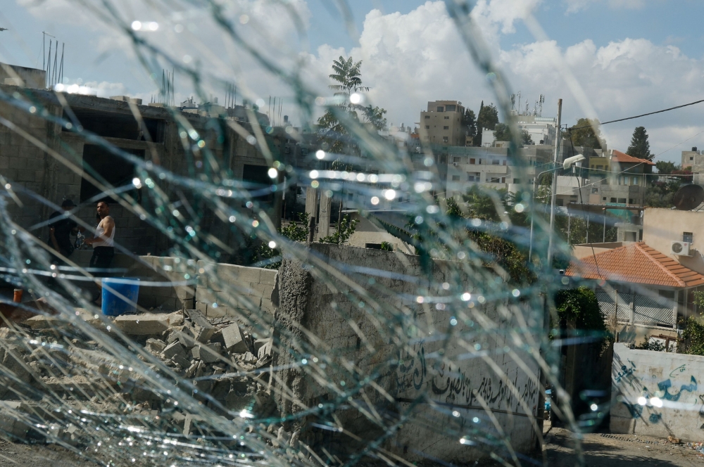 Palestinians are pictured through broken glass window following an Israeli raid in Tulkarm in the Israeli-occupied West Bank October 20, 2023. — Reuters pic