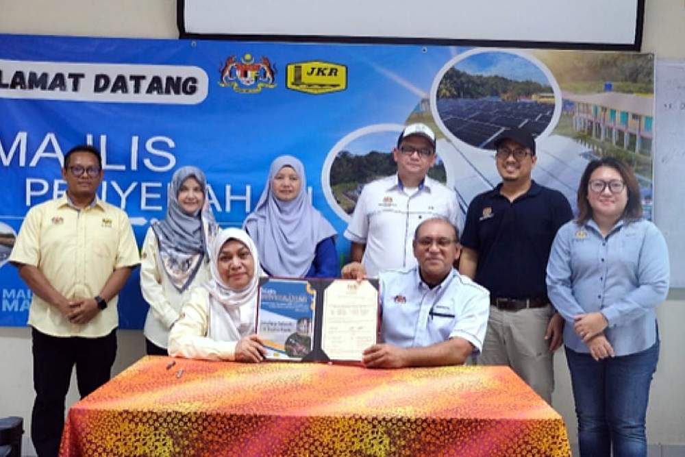 The signing session of the project handover certificated between Hanizan, representing JKR Malaysia, and Mohamed (sitting, right) representing MoE. ― Borneo Post pic