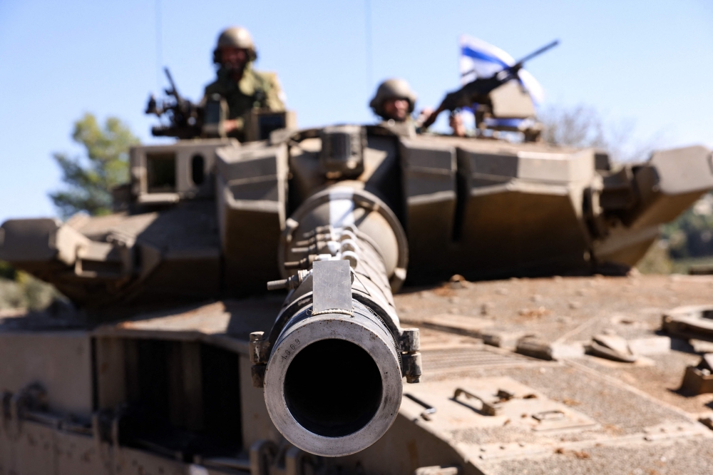 Israeli soldiers sit on a Merkava tank as they man a position at an undisclosed location on the border with Lebanon on October 21, 2023. — AFP pic