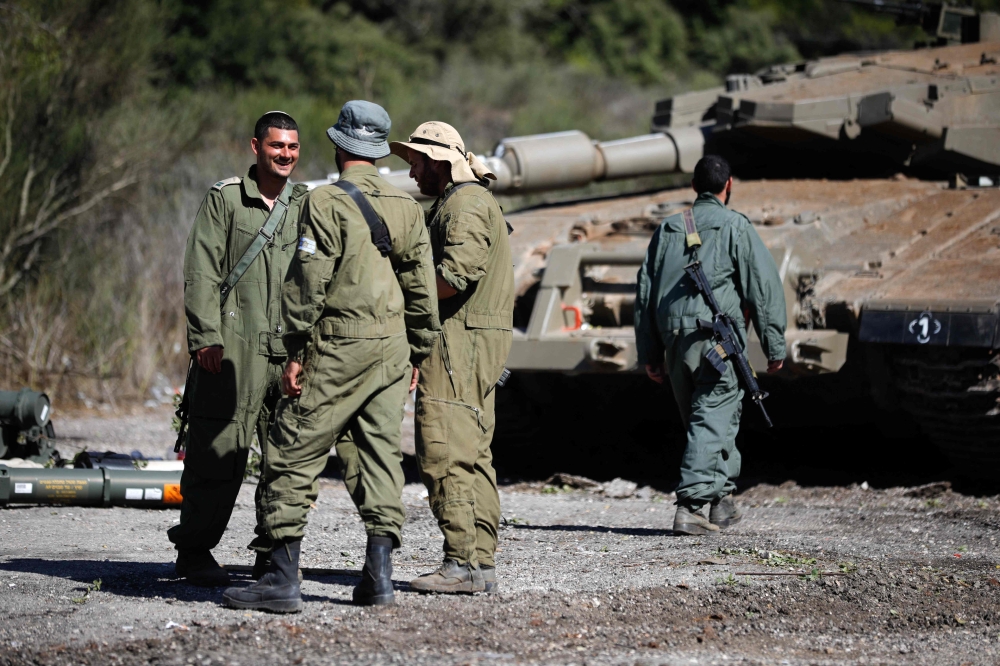 Israeli soldiers stand near a Merkava tank as they man a position at an undisclosed location on the border with Lebanon on October 21, 2023. — AFP pic