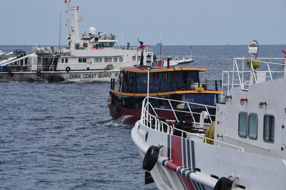 Chinese coast guard ships (left and right) corral a Philippine civilian boat chartered by the Philippine navy to deliver supplies to Philippine navy ship BRP Sierra Madre in the disputed South China Sea, on August 22, 2023. — AFP pic