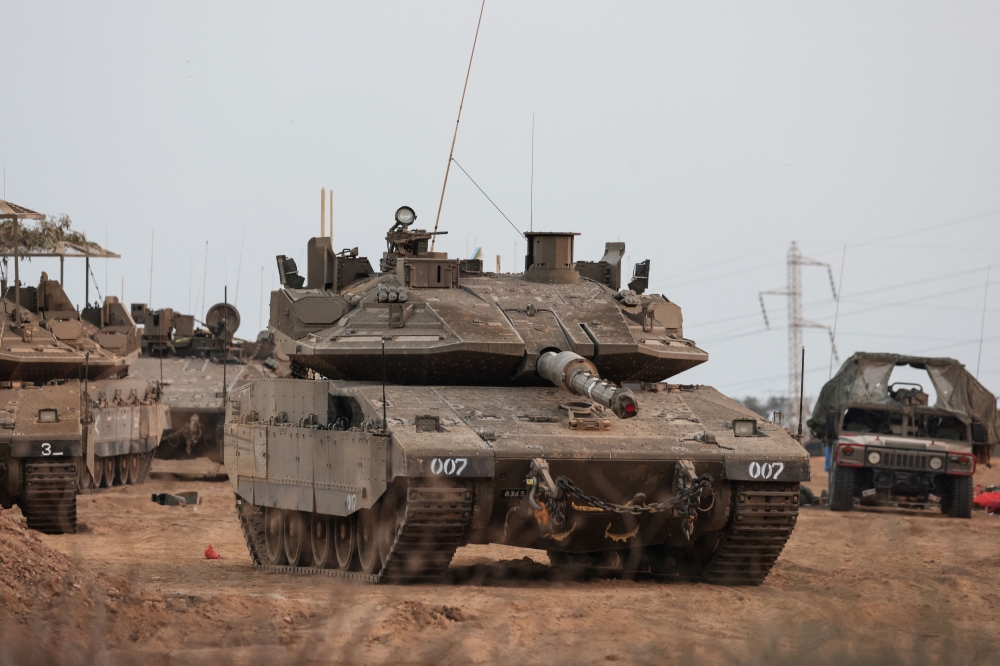 An Israeli tank and military vehicles are seen near Israel's border with the Gaza Strip, in southern Israel, October 22, 2023. — Reuters pic