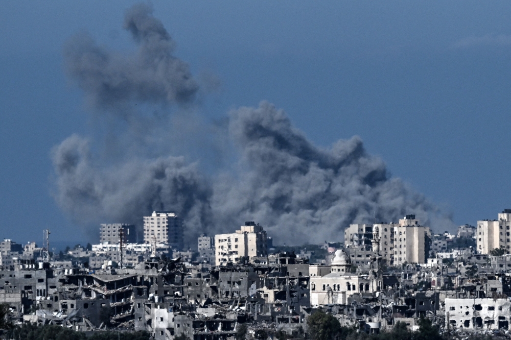 A picture taken from the Israeli side of the border with the Gaza Strip shows smoke rising behind destroyed buildings in the norther-western part of the Palestinian enclave during an Israeli bombing on October 21, 2023. — AFP pic