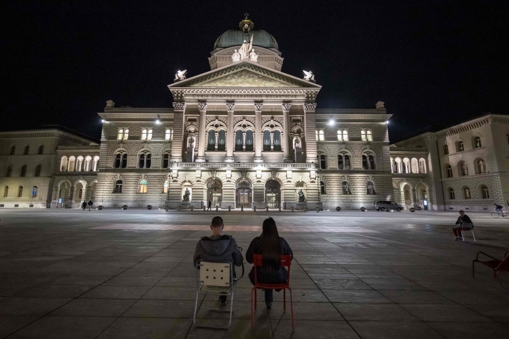 People sit in front of the Swiss House of Parliament during Swiss federal elections to elect a new Parliament, in Bern on October 22, 2023. — AFP pic