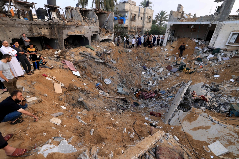 Palestinians stand around a crater from an Israeli strike in Khan Yunis in the southern Gaza Strip.