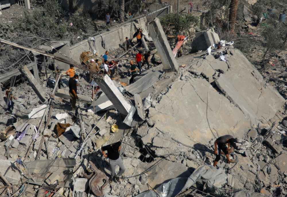 Palestinians search for casualties following an Israeli strike on a house, in Khan Younis, in the southern Gaza Strip, October 25, 2023. — Reuters pic