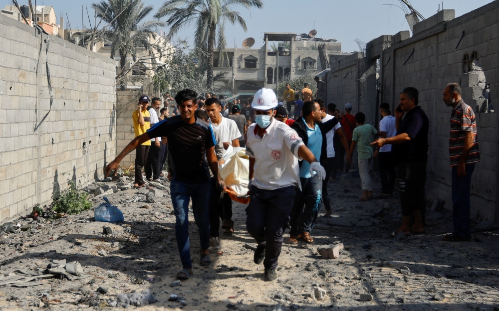 Palestinians evacuate a casualty following an Israeli strike on a house, in Khan Younis, in the southern Gaza Strip, October 25, 2023. — Reuters pic
