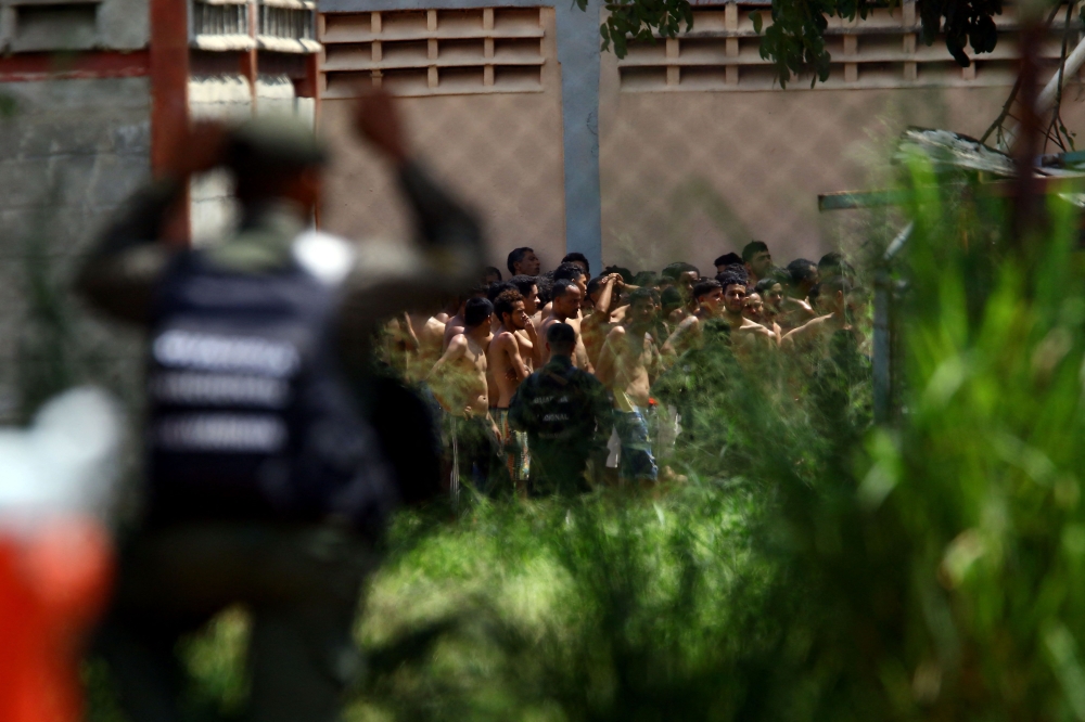 Members of the Bolivarian National Guard stand guard outside the Tocuyito prison as inmates wait to be transferred. — AFP pic
