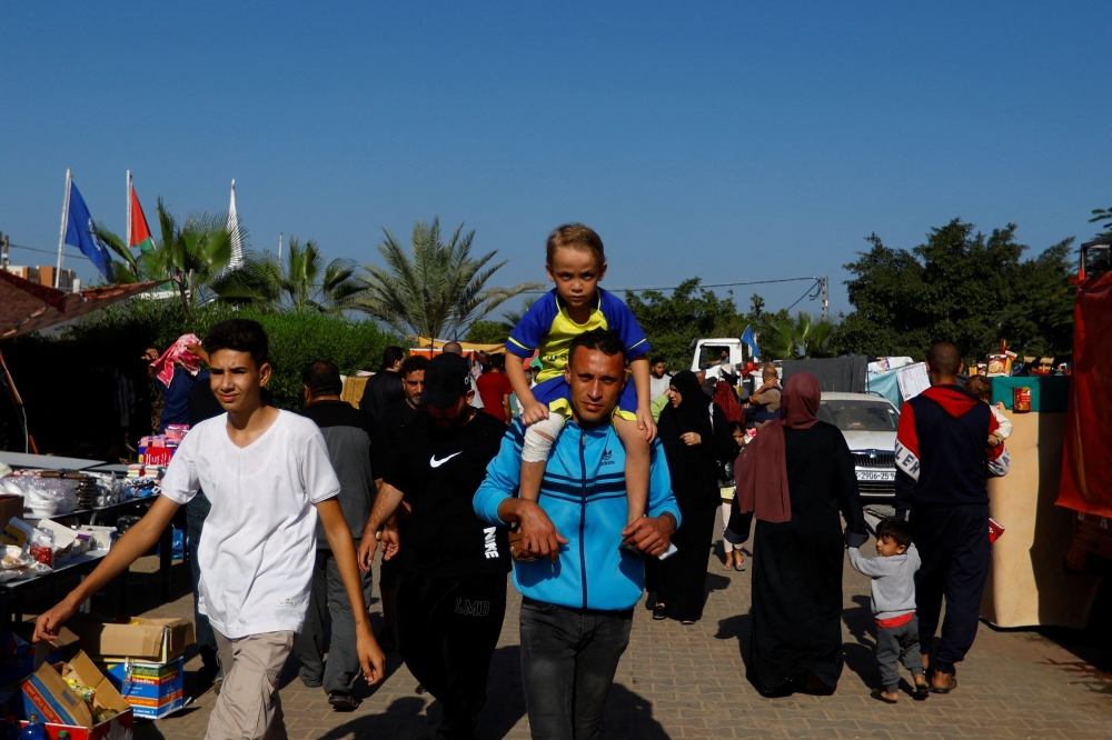 Palestinians, who fled their houses amid Israeli strikes, walk as they take shelter at a tent camp at a United Nations-run centre, after Israel's call for more than 1 million civilians in northern Gaza to move south, in Khan Younis in the southern Gaza Strip, October 26, 2023. — Reuters pic