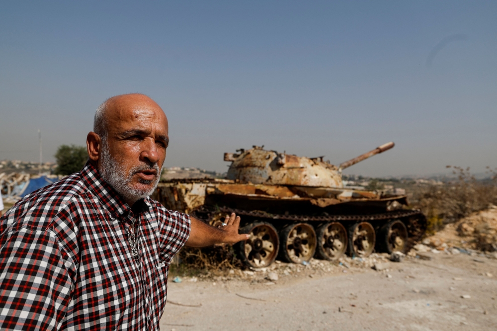 Jamil Salameh, 56, who witnessed the Israeli shelling that killed more than 100 people in 1996 and dozens more in an Israeli airstrike in 2006, talks to a journalist beside what he said the remains of a destroyed Israeli tank in Qana, Lebanon October 24, 2023. — Reuters pic