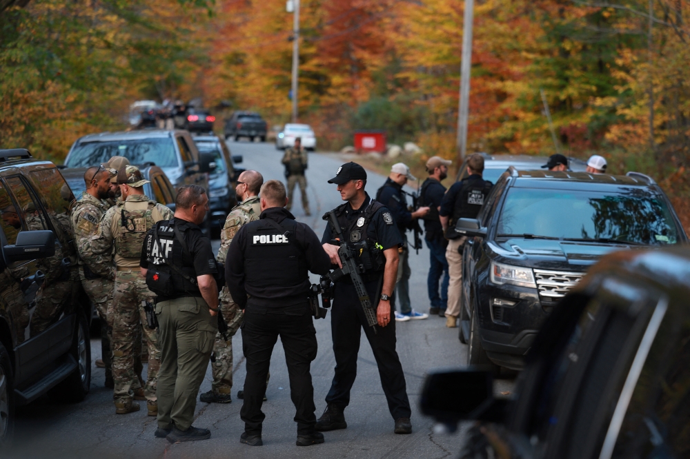Law enforcement officials gather in the road leading to the home of the suspect being sought in connection with two mass shootings on October 26, 2023 in Bowdoin, Maine. — Joe Raedle/Getty Images/AFP pic