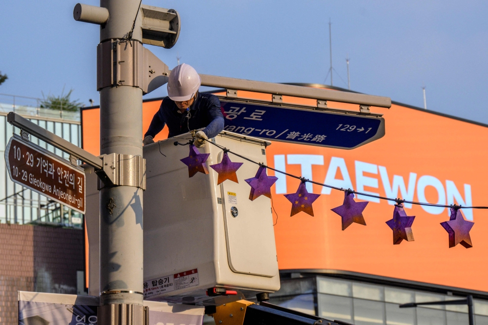A worker displays star shaped lanterns in memory of victims of the October 29, 2022 crowd crush that killed more than 150 people during Halloween celebrations, near the site of the tragedy in the popular Itaewon nightlife area in Seoul on October 25, 2023. — AFP pic