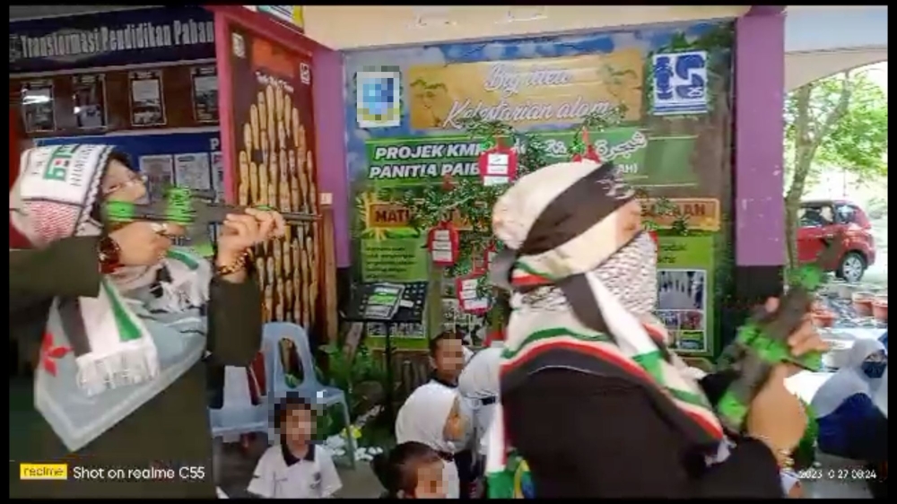 Screenshot of a video showing teachers marching to show their solidarity with Palestine in a school, with several of them brandishing toy firearms.