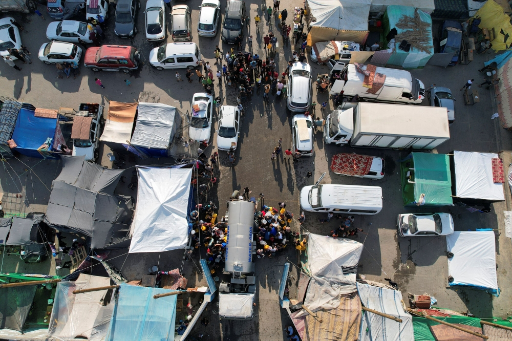 Palestinians gather to collect water from a truck at a United Nations-run school where displaced Palestinians shelter, as the conflict between Israel and the Palestinian Islamist group Hamas continues, in central Gaza Strip October 27, 2023. — Reuters pic