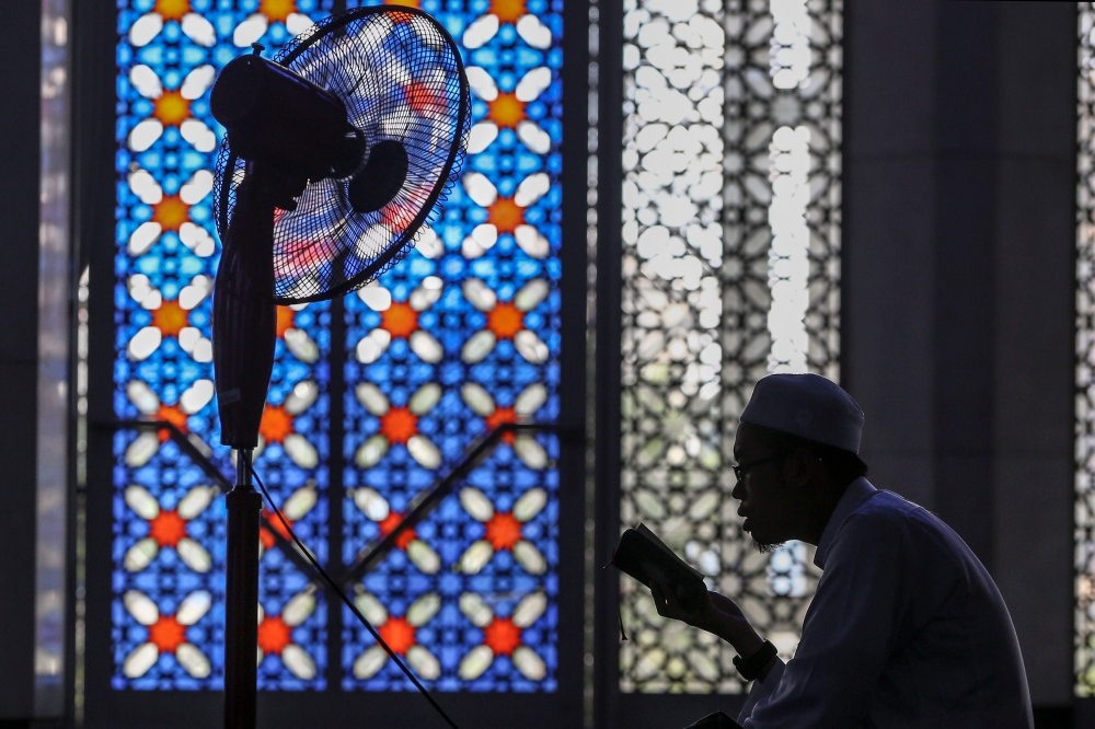 The silhouette of a man is seen as he reads the Quran during Ramadan at the Sultan Salahuddin Abdul Aziz Shah Mosque in Shah Alam May 18, 2019. Denmark’s government today presented a modified version of its bill to ban Quran burnings, following criticism that its first draft limited freedom of expression and would be difficult to enforce. — Picture by Yusof Mat Isa
