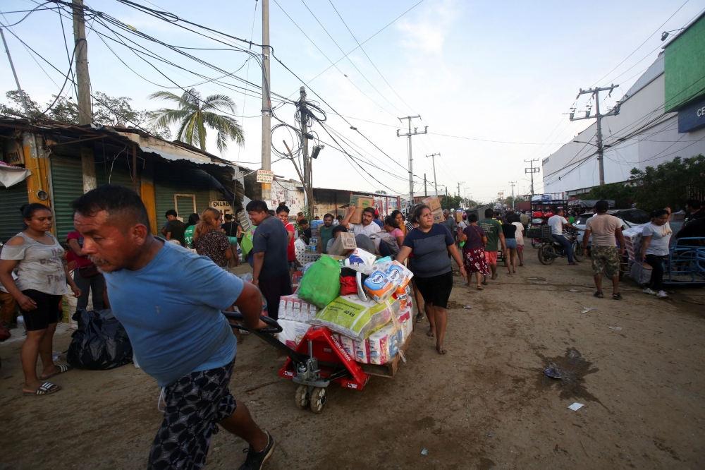 People leave with goods after looting a local supermarket in the aftermath of Hurricane Otis, near Acapulco October 26, 2023. — Reuters pic