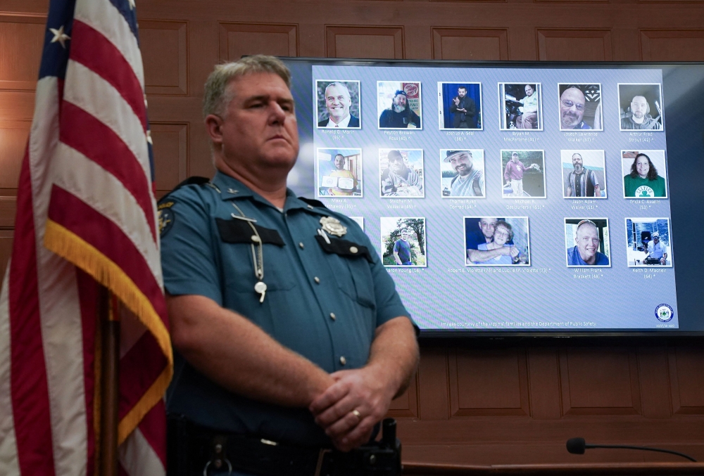 A police officer listens, next to a screen displaying the pictures of the people killed in a deadly mass shooting, as their names are read during a press conference at City Hall in Lewiston, Maine October 27, 2023. ― Reuters pic