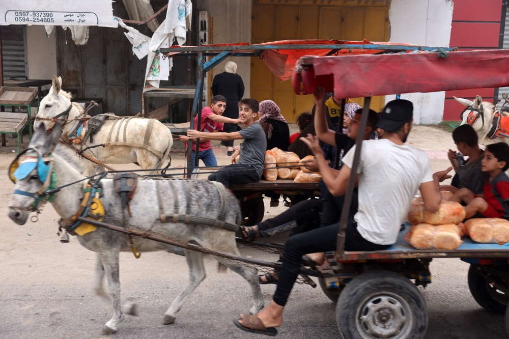 People transport bread as they ride a donkey-pulled carts in Gaza City on October 28, 2023. — AFP pic