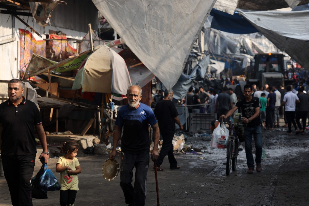 People walk along a street in the aftermath of Israeli strikes in Gaza City on October 28, 2023. — AFP pic
