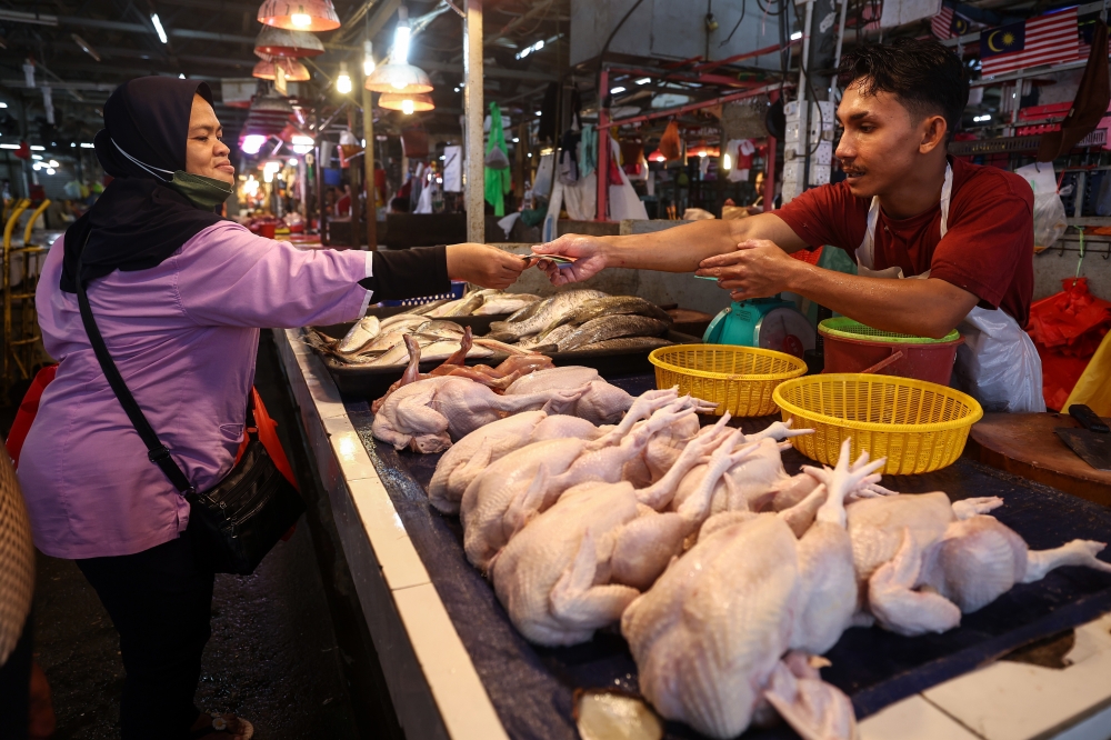 A customer buys chicken at the Chow Kit wet market in Kuala Lumpur, October 30, 2023. — Bernama pic 