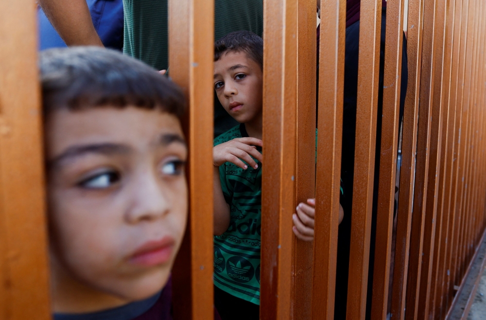 Children look on from behind a gate as mourners attend a funeral of Palestinians killed in Israeli strikes, in Khan Younis in the southern Gaza Strip October 31, 2023. — Reuters pic