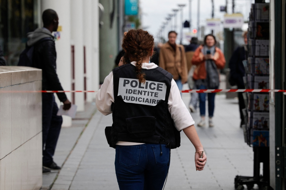 A French police officer wears a jacket, identifying herself as ‘Police identite judiciaire’), while walking from a metro station after a woman making threats on an RER train was shot and wounded by police, in Paris on October 31, 2023. — AFP pic