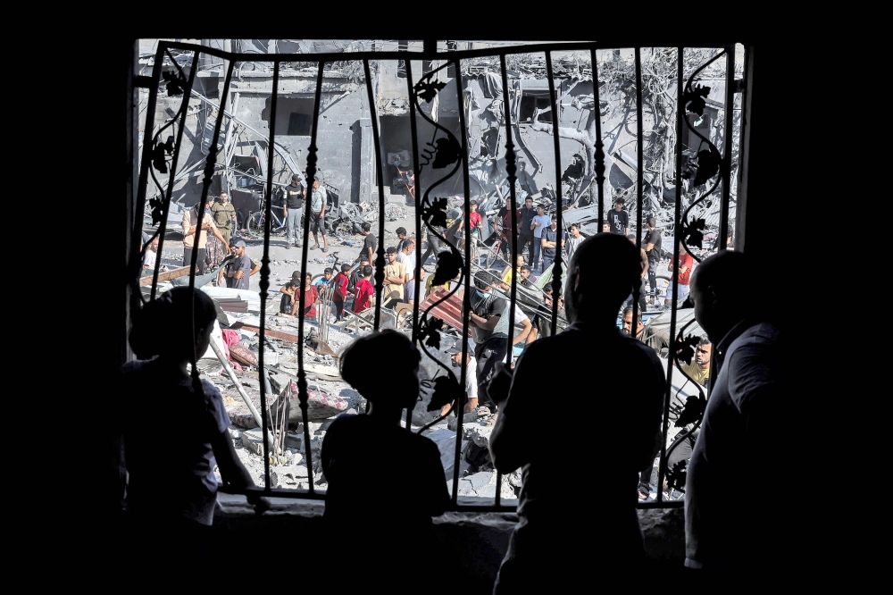 People stand behind the metal mesh that covered the window of a building that was hit by Israeli bombardment in Rafah in the southern Gaza Strip on October 31, 2023 amid ongoing battles between Israel and the Palestinian Hamas movement. — Reuters pic