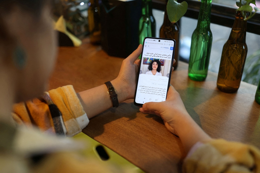 An Iranian woman sees the news of Iranian activist Narges Mohammadi winning the Nobel Peace Prize on her mobile phone, in a cafe in Tehran, Iran, October 6, 2023. — Majid Asgaripour/Wana(West Asia News Agency) via Reuters