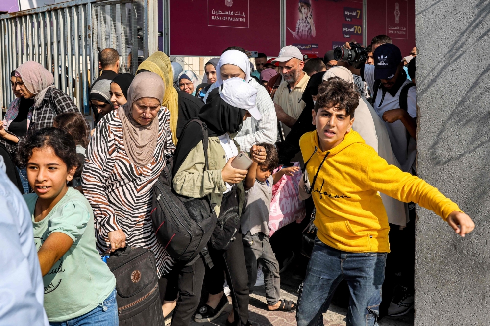 People walk through a gate to enter the Rafah border crossing to Egypt in the southern Gaza Strip on November 1, 2023. — AFP pic
