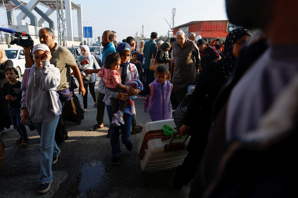 Palestinians with dual citizenship walk as they wait for permission to leave Gaza, amid the ongoing conflict between Israel and Palestinian Islamist group Hamas, at the Rafah border crossing with Egypt, in Rafah in the southern Gaza Strip, November 2, 2023. — Reuters pic
