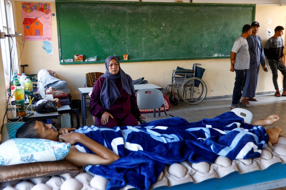 Son of Palestinian woman Salwa Najar lies in a bed as his mother sits by, at a school turned to a shelter, as hospitals are overwhelmed, amid the ongoing conflict between Israel and Palestinian Islamist group Hamas, in Khan Younis, in the southern Gaza Strip, October 31, 2023. — Reuters pic