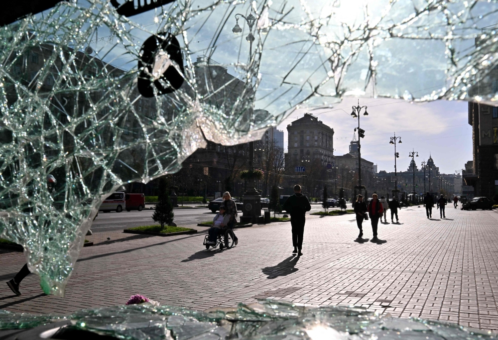 This photograph taken through the broken windshield of a car, destroyed on the frontline and set as an exhibit, shows people walking in the center of Kyiv on October 31, 2023, amid the Russian invasion in Ukraine. — AFP pic