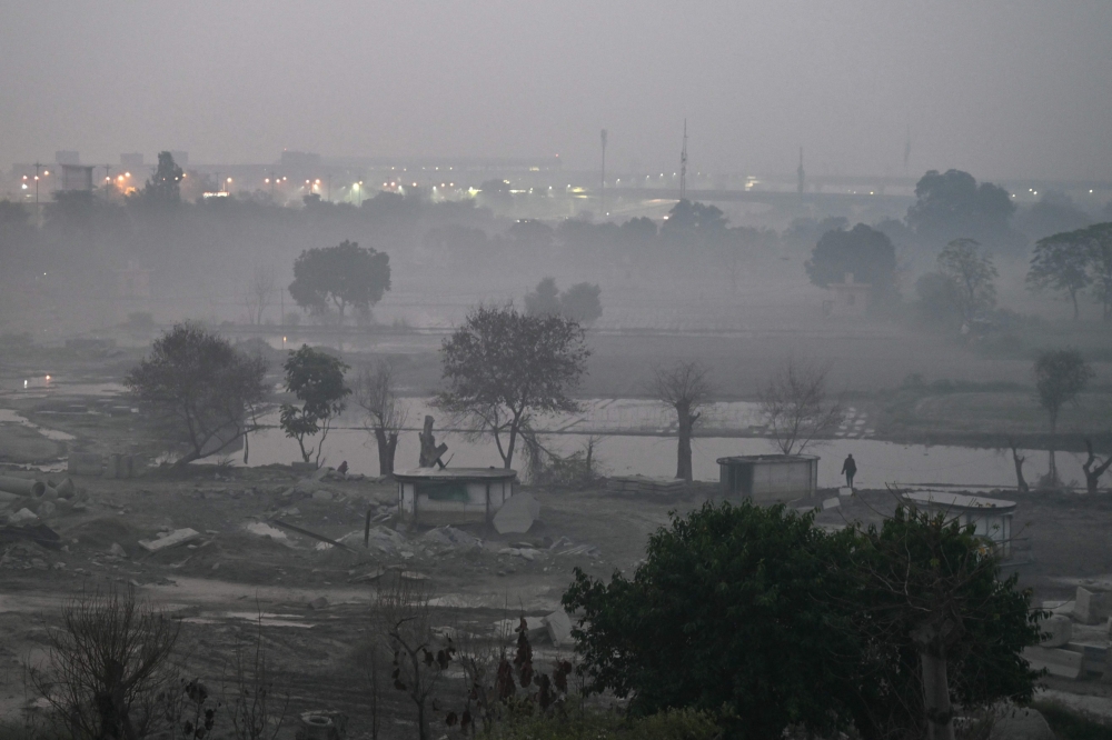 A person walks in smoggy conditions at Yamuna flood plains in New Delhi on October 31, 2023. — AFP pic