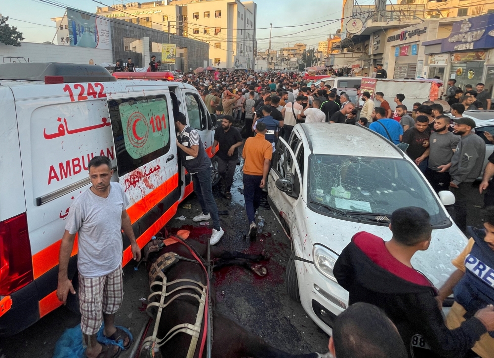 Palestinians check the damages after a convoy of ambulances was hit, at the entrance of Shifa hospital in Gaza City November 3, 2023. — Reuters pic
