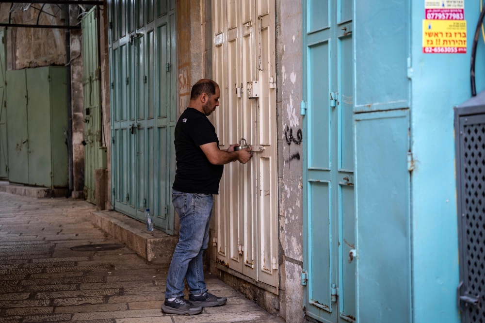 A Palestinian man locks the door of a shop in the empty alleys of Jerusalem's Old City on November 2, 2023. — AFP pic
