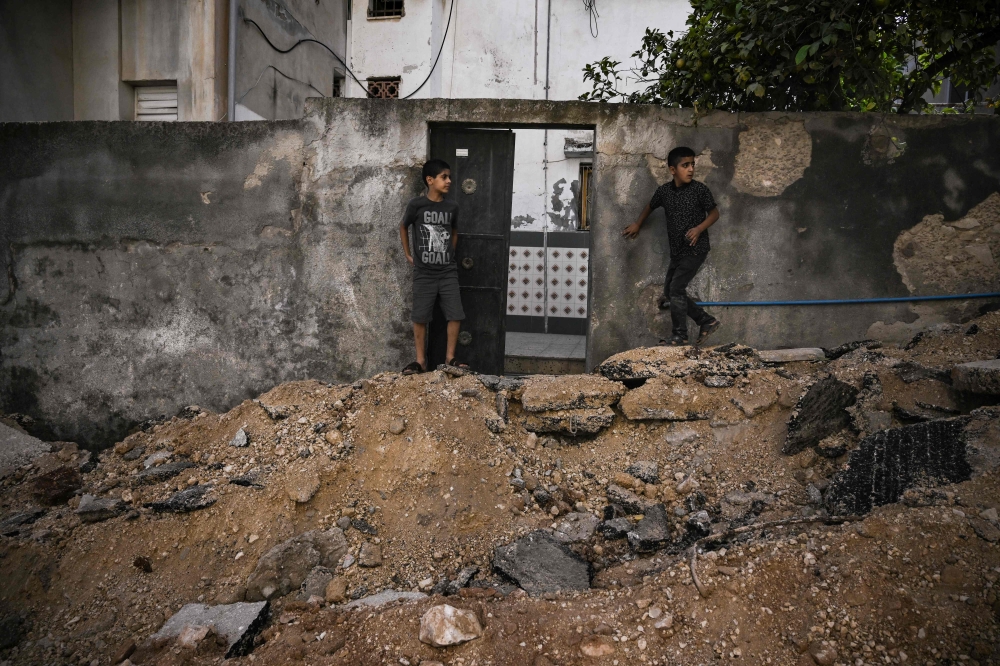 Palestinian boys stand on the edge of a road ripped up by an Israeli manned bulldozer in the Jenin refugee camp. — AFP pic