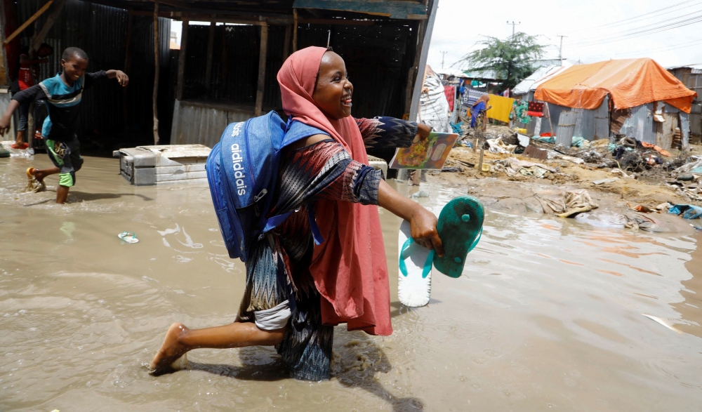 An internally displaced Somali school girl wades through flood waters outside their makeshift shelter following heavy rains at the Al Hidaya camp for the internally displaced people on the outskirts of Mogadishu, Somalia November 6, 2023. — Reuters pic