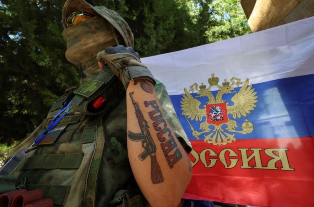 A participant stands next to a Russian state flag at an exhibition showcasing volunteers’ product range, manufactured to supply the needs of service members involved in Russia’s military campaign in Ukraine, in Yevpatoriya, Crimea, July 29, 2023. A tattoo reads: ‘Russia’. — Reuters pic