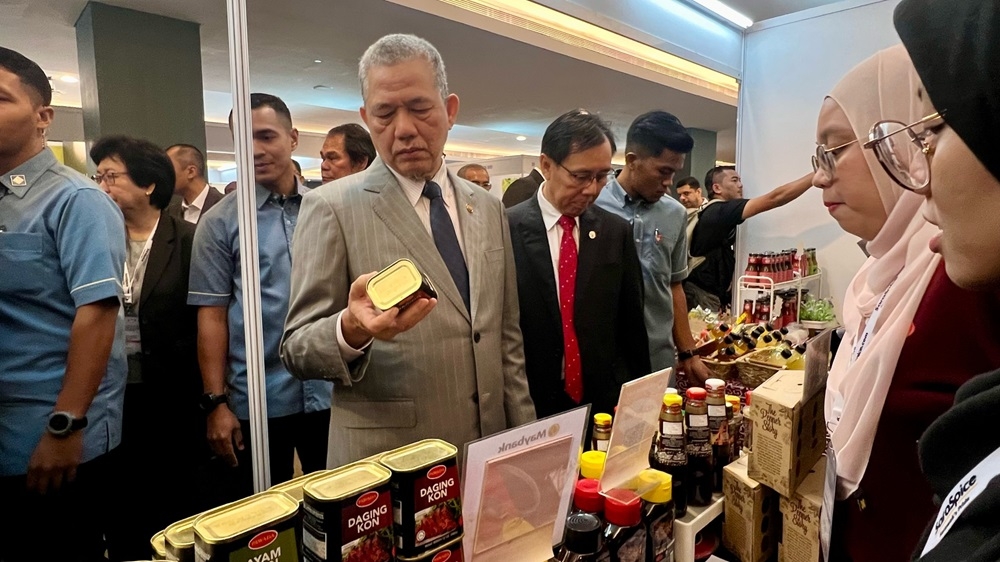 Fadillah (third from right) takes a look at a can of corned beef on display during his visit to one of the exhibition booths at the International Special Exhibition held in conjunction with the 51st IPC ASM. — Borneo Post Online pic