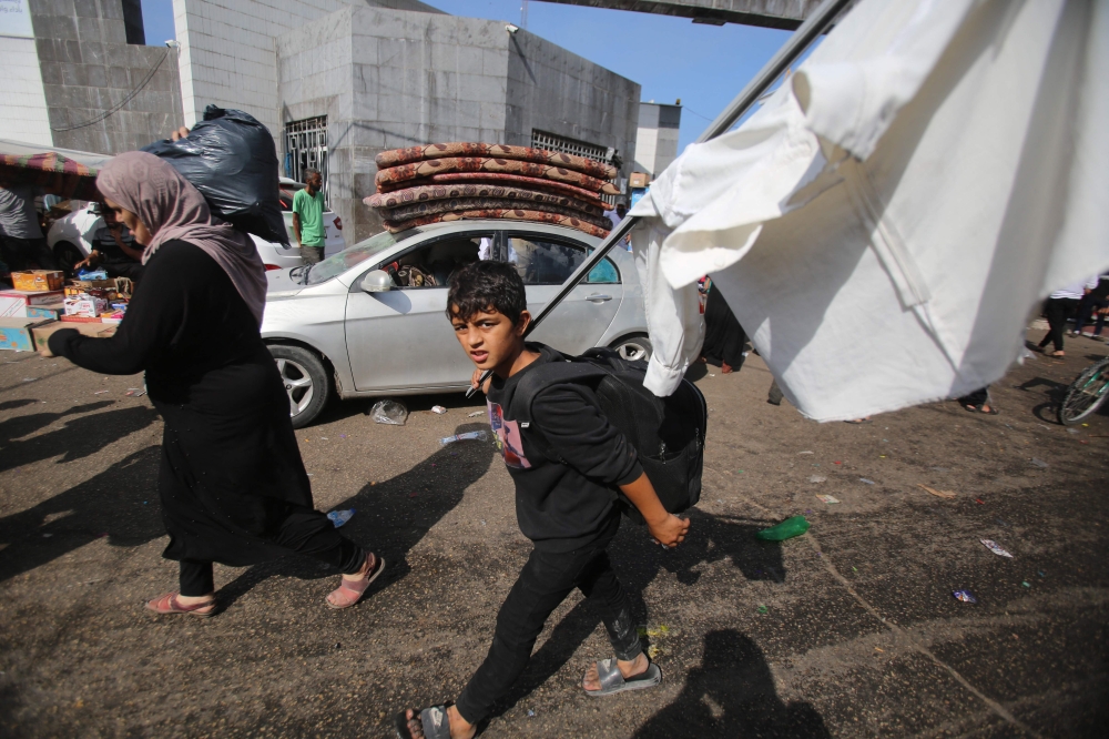 A Palestinian boy carries a make-shift white flag as he arrives with his mother near the Al-Shifa hospital in Gaza City on November 6, 2023, amid ongoing battles between Israel and the Palestinian Hamas movement. — AFP pic